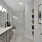 Large well lit bathroom with large mirror and gray cabinets 
